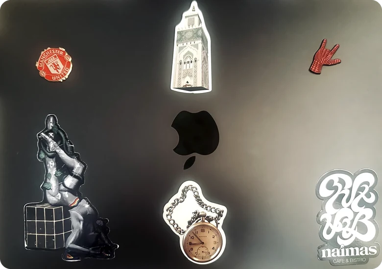 The lid of his MacBook Pro, covered in stickers